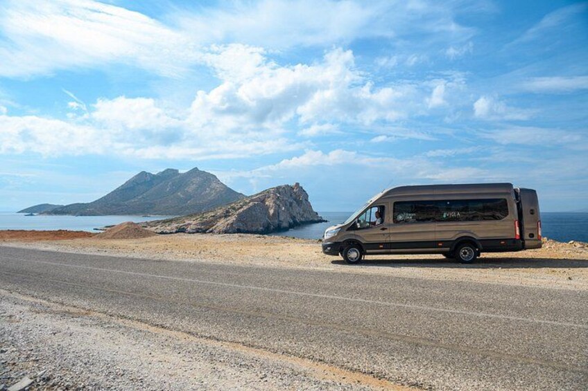 A van parked on a coastal road with a mountainous backdrop. 4