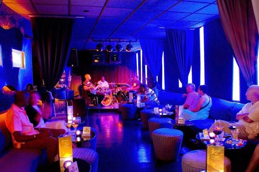 A band performing on stage with a seated audience in a dimly lit venue. 3