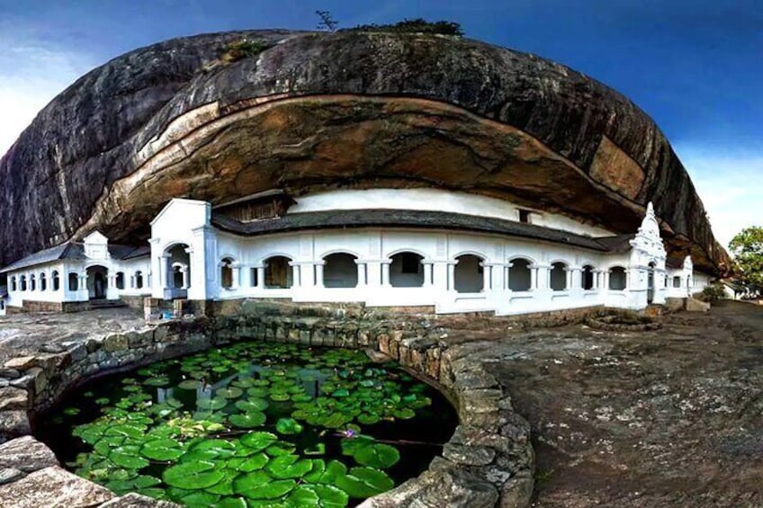 A large rock formation with a temple built on top, surrounded by a pond with lily pads. 4