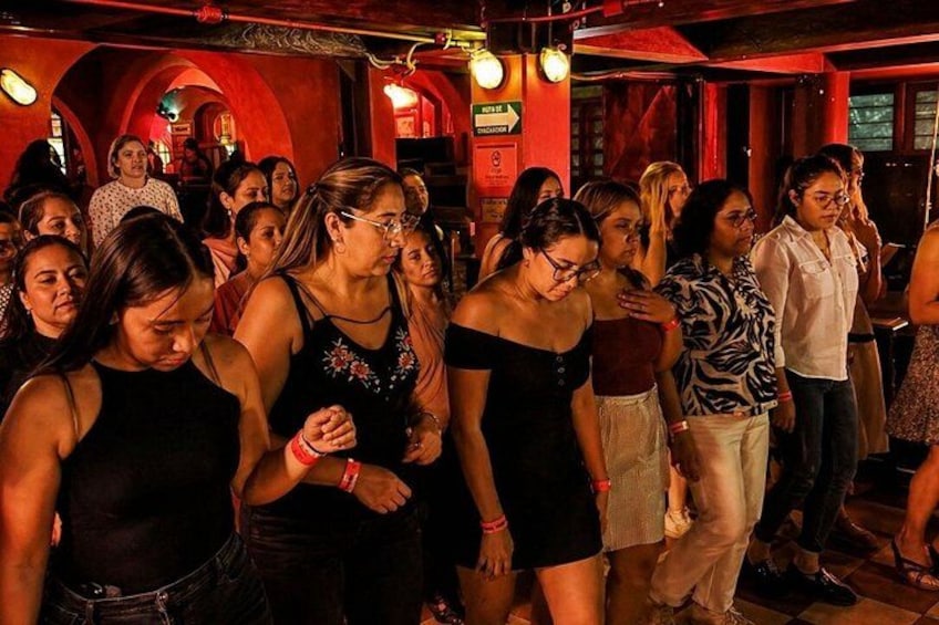Een groep mensen danst in een zwak verlichte locatie met rode muren en bogen. 2