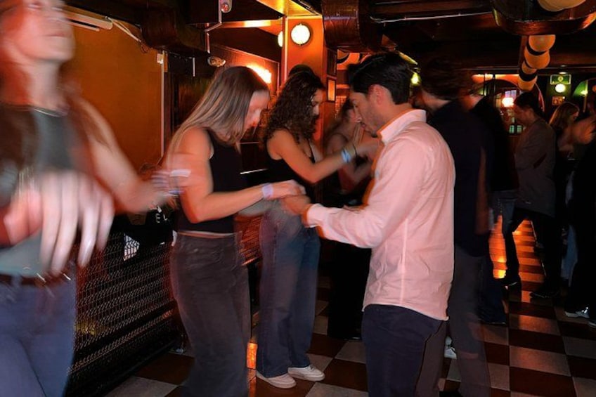 Mensen dansen in een zwak verlichte ruimte met een geruite vloer. 4
