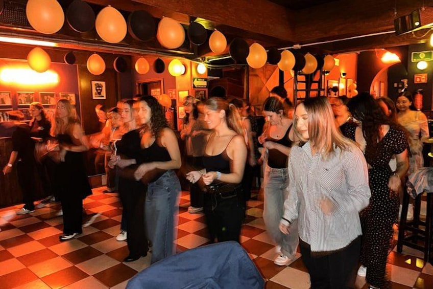 Een drukke binnenruimte met zwart-witte vloertegels, ballonnen en mensen die met elkaar praten. 5