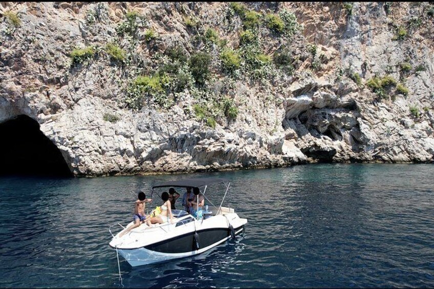 A small boat with people on a rocky coastline. 1