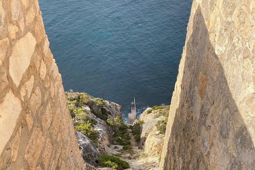 Un escalier en pierre qui descend vers un phare situé au bord de la mer. 3