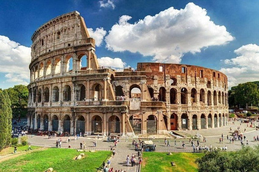 The Colosseum in Rome with its arches and ruins, surrounded by green spaces and people. 3