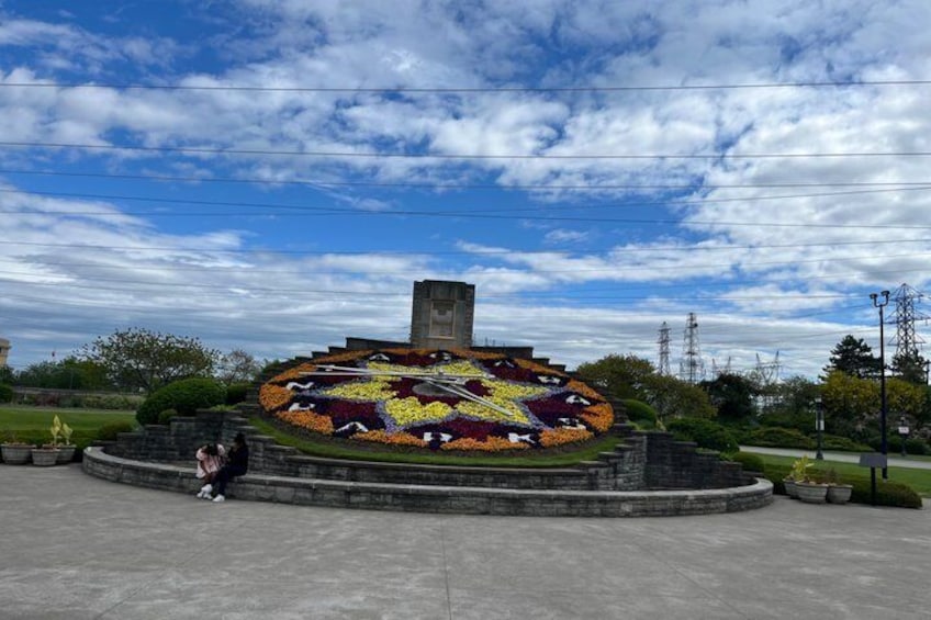 A circular flower arrangement with a central monument, surrounded by a paved area. 4