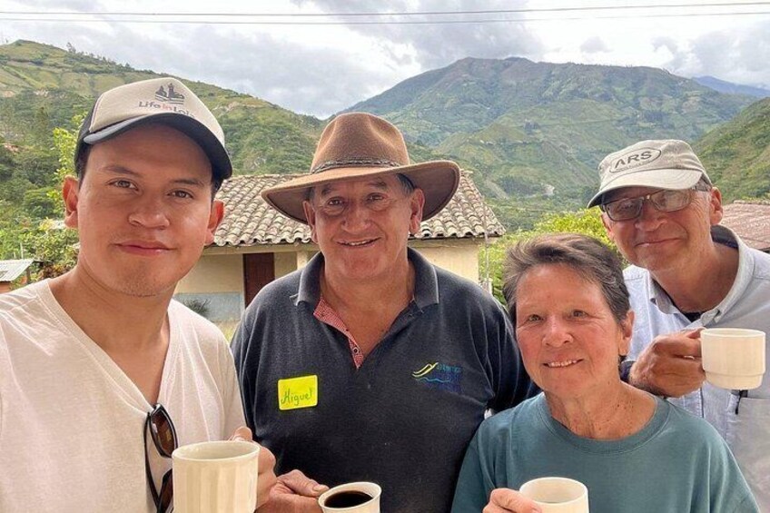 Four people standing outdoors with a mountainous landscape in the background. 4
