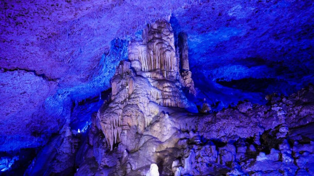 A cave with stalactites and stalagmites illuminated by blue lighting. 1