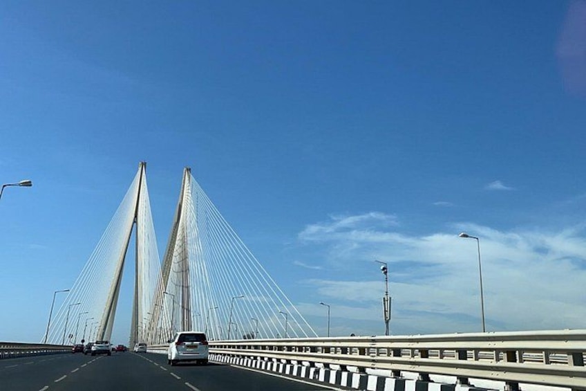 Een kabelbrug met twee torens, verkeer op de weg en een heldere blauwe lucht. 3