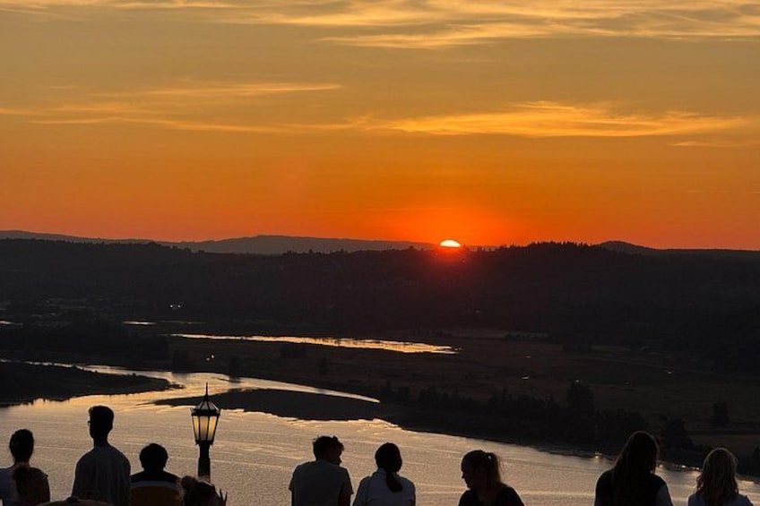 Un atardecer sobre un río, con siluetas de personas y un farol. 1