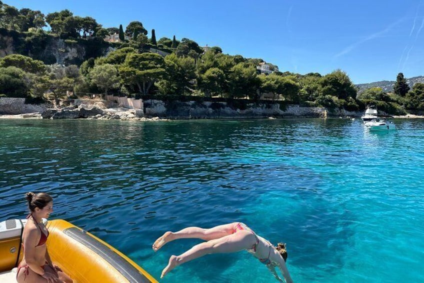 A clear blue sea, a boat, and a person diving. 4