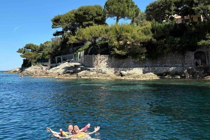 A coastal scene with clear water, a rocky shoreline, and a stone wall with trees. 5