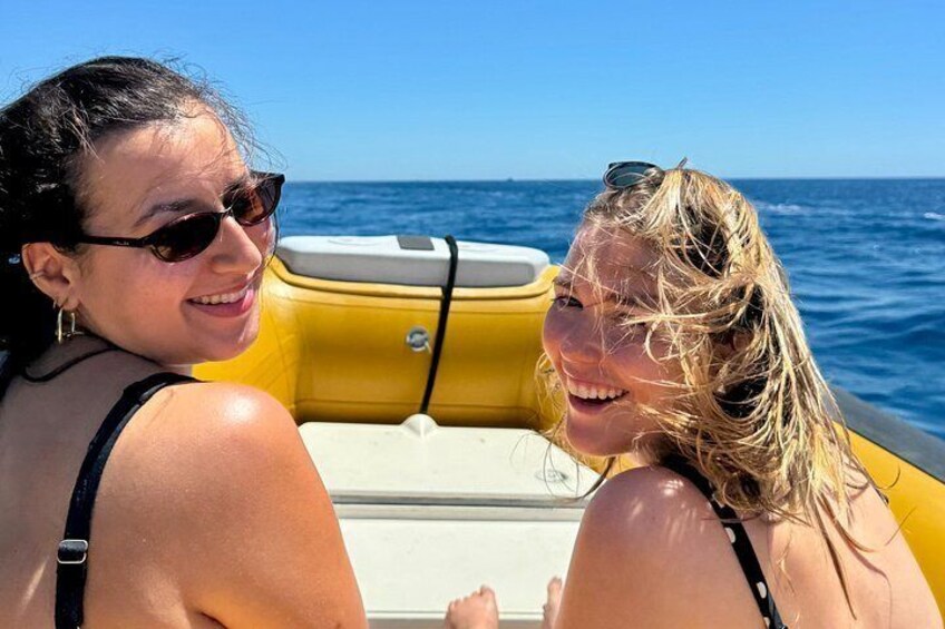 Two people on a yellow boat with a clear blue sky and ocean in the background. 2