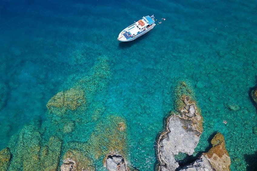 A boat on clear turquoise water with rocky formations. 3