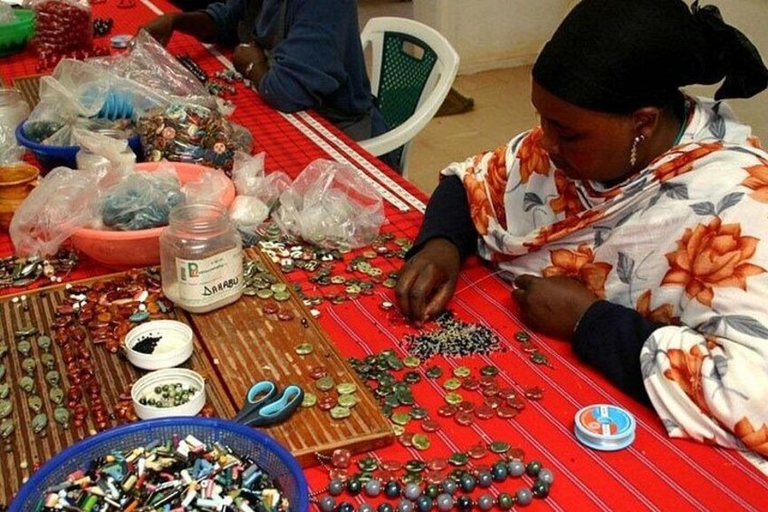 A person sorting beads and jewelry on a table with various containers and tools. 2