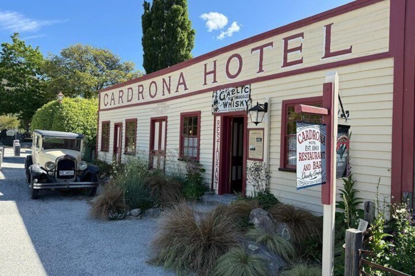 A historic building labeled 'Cardrona Hotel' with a vintage car parked in front. 3