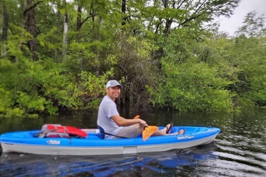 A person in a blue kayak on a river surrounded by dense green foliage. 3