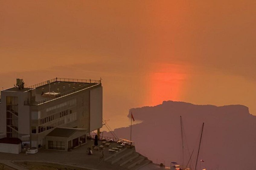 A building with a flat roof, a parking lot, and a large body of water in the background. 5