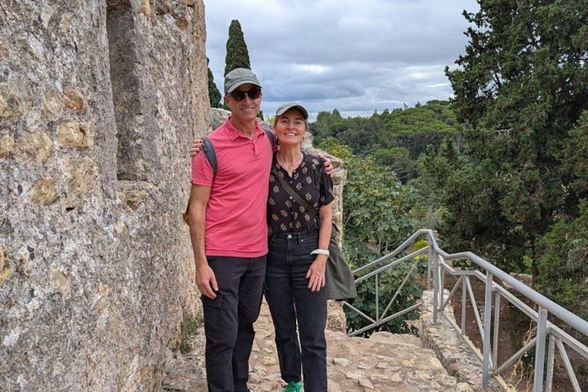 A man and a woman standing on stone steps with a forested landscape in the background. 2