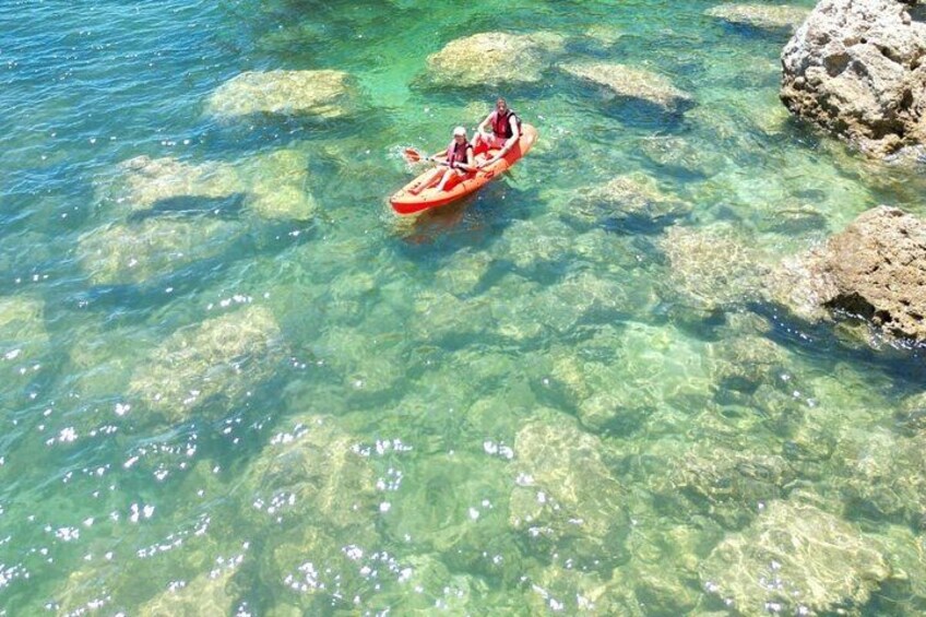 A person kayaking in clear water with rocks. 1