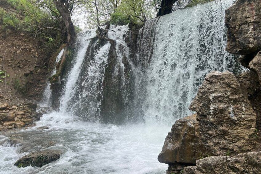 A waterfall cascading over rocks, surrounded by greenery. 4