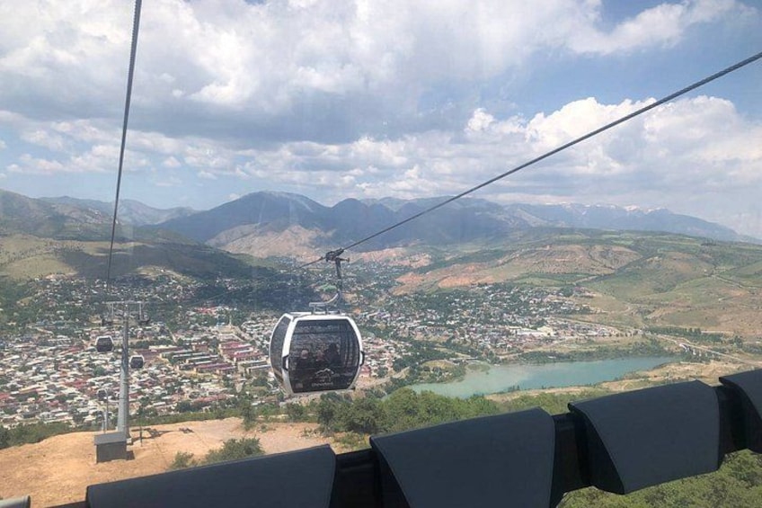 A cable car moving over a mountainous landscape with a town below. 2