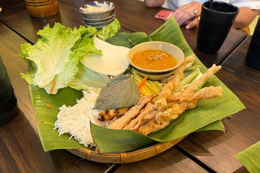 A meal served on a banana leaf with fried items, a bowl of sauce, and fresh vegetables. 5