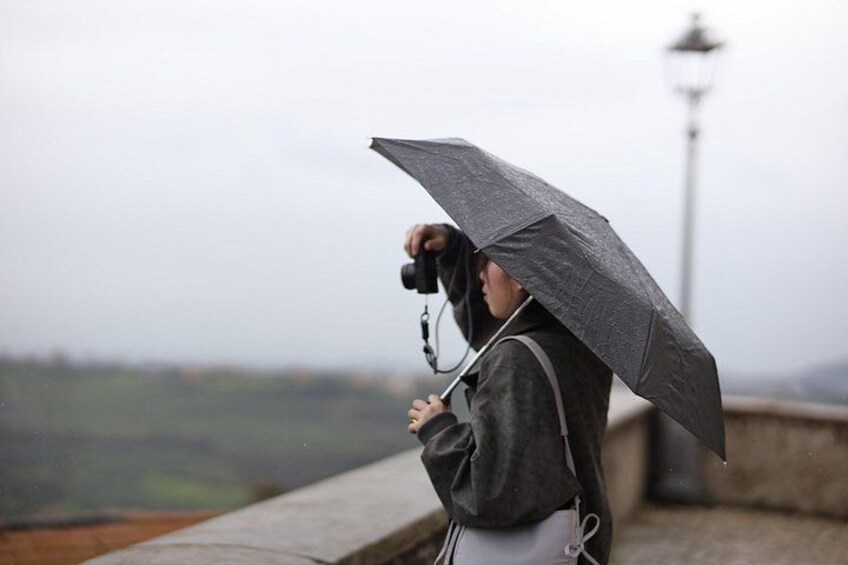 A person holding an umbrella, wearing a jacket, and standing near a lamppost. 1