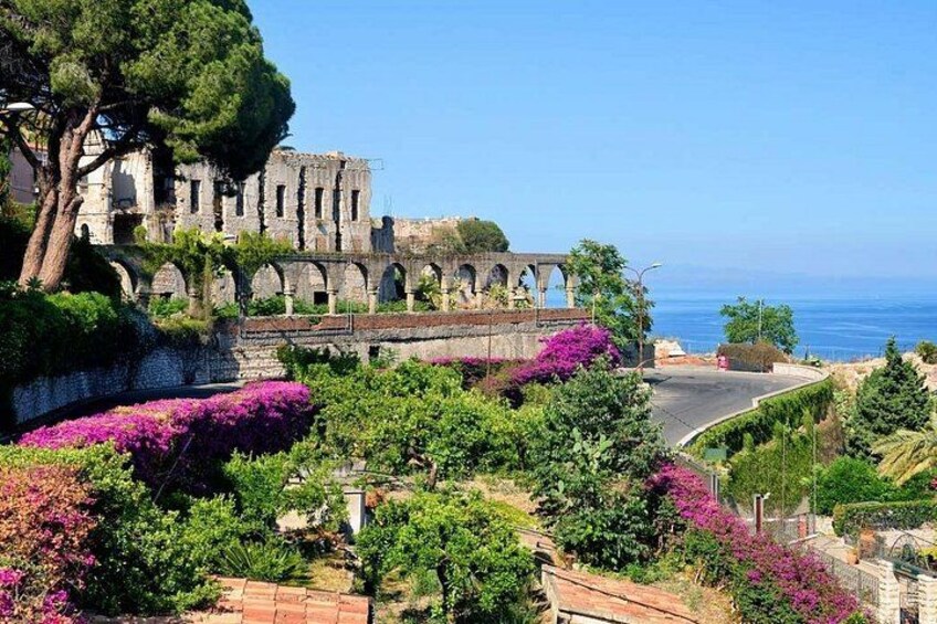 Un paysage côtier avec des ruines, des plantes en fleurs et un ciel dégagé. 4