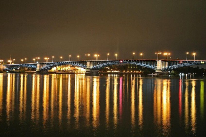 A lit bridge over water at night with reflections. 5
