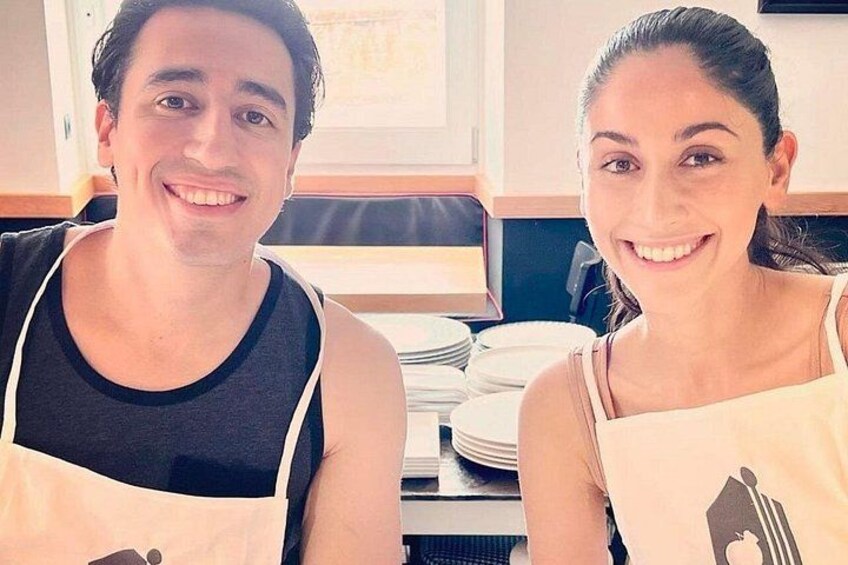 Two people sitting at a table with plates and a window in the background. 4