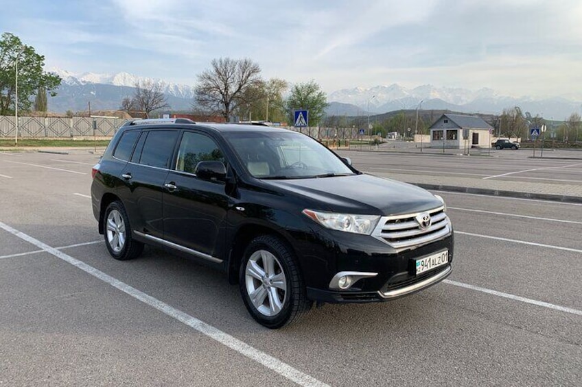 A black SUV parked in a lot with mountains in the background. 3
