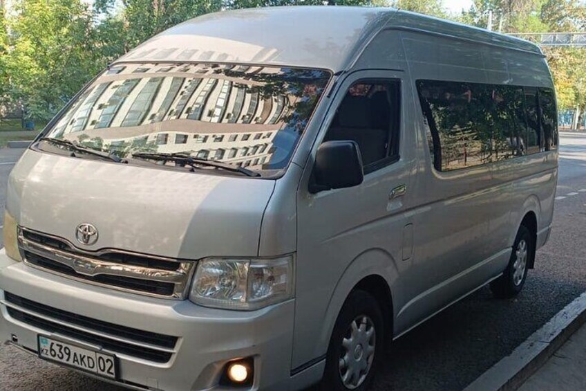 A silver Toyota van parked on a street with trees in the background. 2