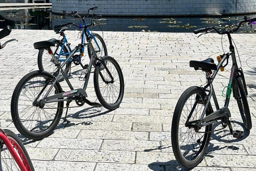 Two bicycles parked on a cobblestone pavement. 3