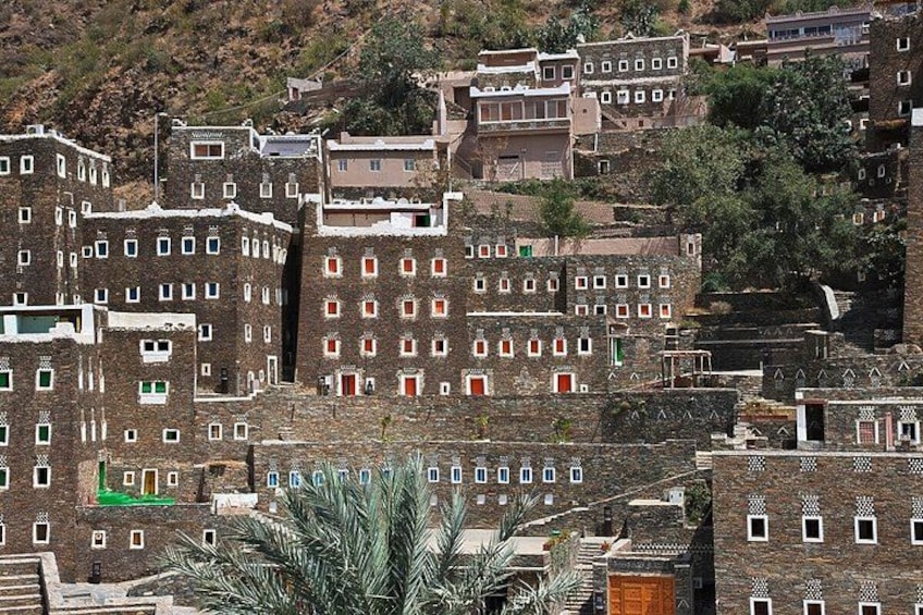 A traditional village with multi-story buildings, narrow streets, and a hilly backdrop. 5