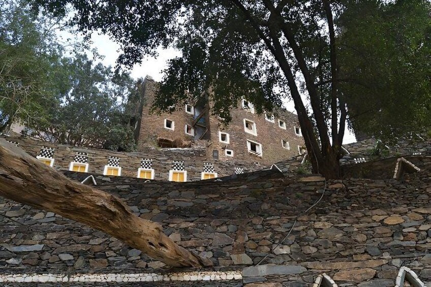 A stone staircase leading up to a brick building with multiple windows, surrounded by trees. 2