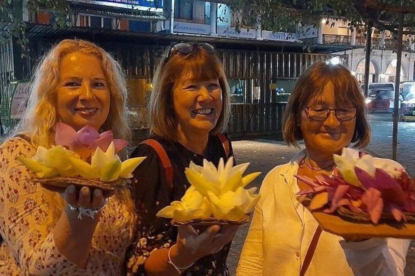 Tre personer holder lotusblomster. 3