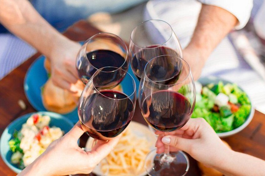 Des personnes qui trinquent avec des verres de vin, une salade et une assiette de frites. 3