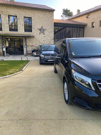 A building with a stone facade and a black Mercedes van parked in front. 3