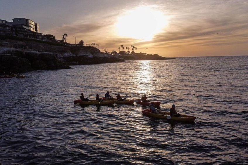 A sunset over a body of water with people kayaking. 4