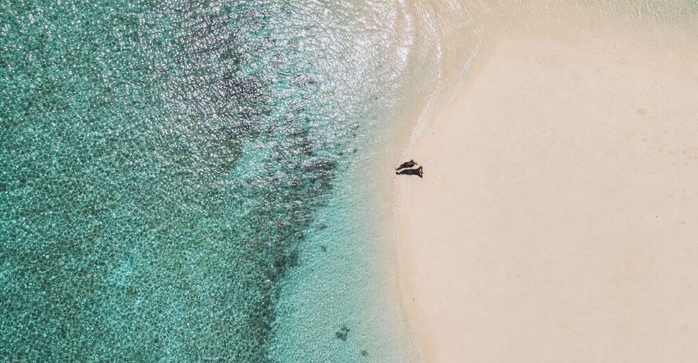 A beach with clear turquoise water and a person walking along the shore. 5