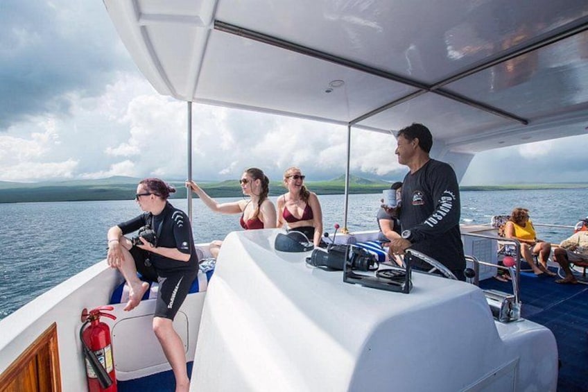 Ein Boot mit Personen auf dem Deck, eine Person am Steuer und einem Feuerlöscher an der Seite. 1