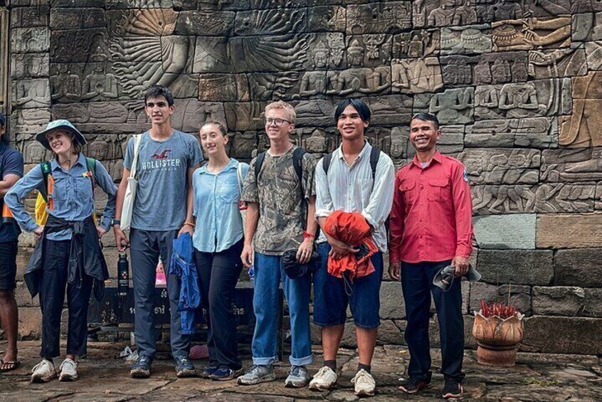Een groep mensen staat voor een stenen muur met gravures. 2
