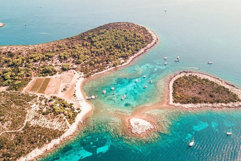 An aerial view of a coastal area with clear turquoise waters, a sandy beach, and several small islands with dense vegetation. 4