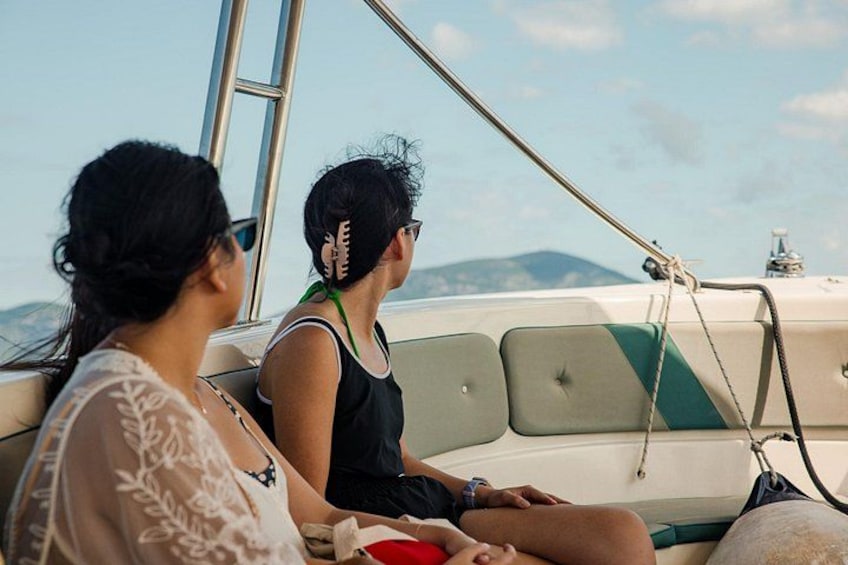 Two people on a boat with a view of the sea and distant mountains. 3