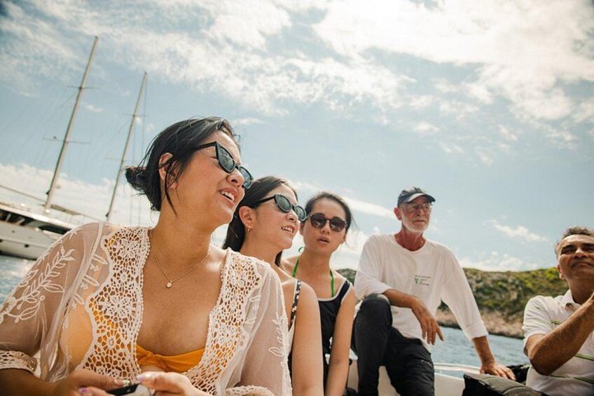 A group of people on a boat with a clear sky and distant boats in the background. 3