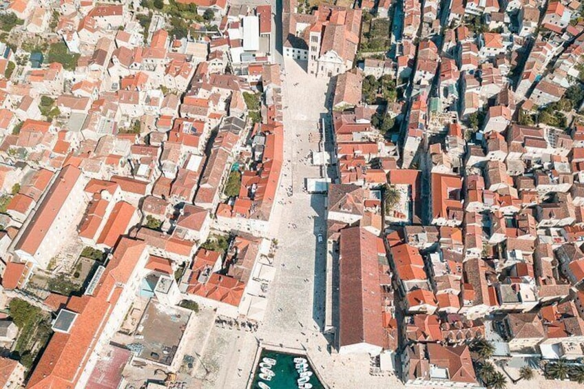 An aerial view of a densely packed urban area with narrow streets and red-roofed buildings. 4