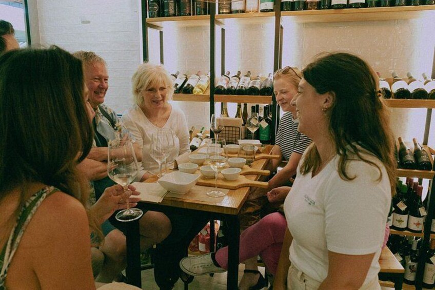 A group of people seated around a table with wine bottles and glasses. 5