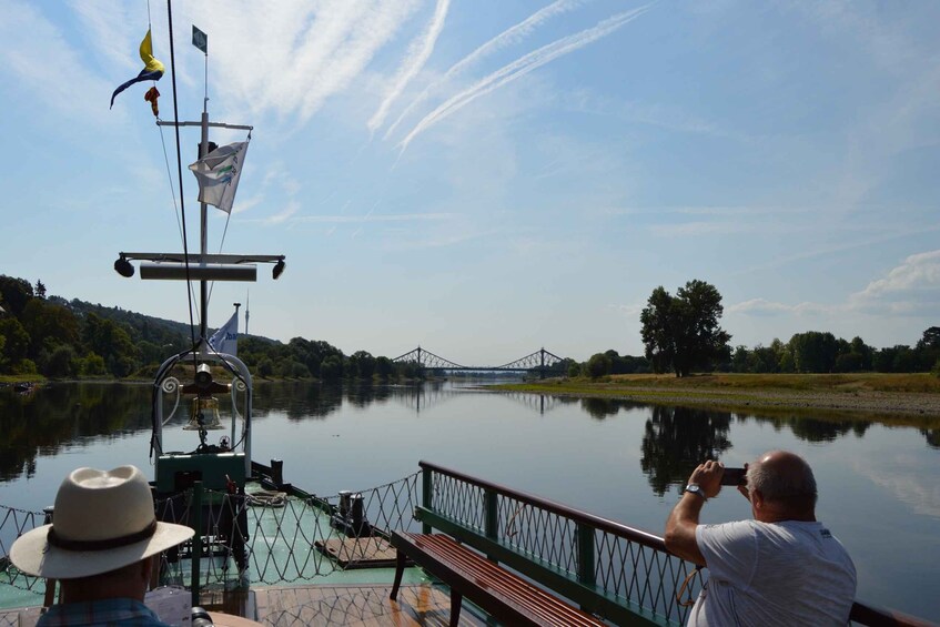 A boat on a calm river with a bridge in the background. 3