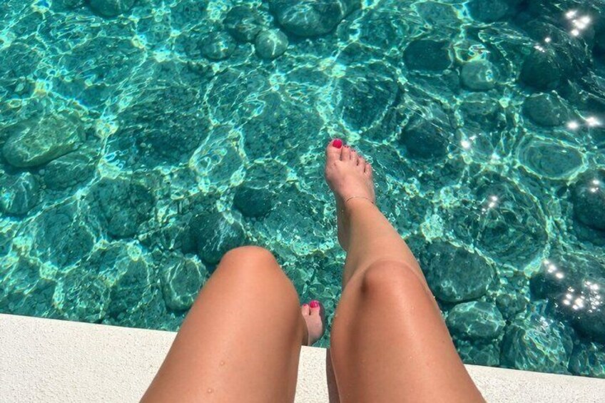 Piernas de alguien en una piscina con agua cristalina y rocas. 5